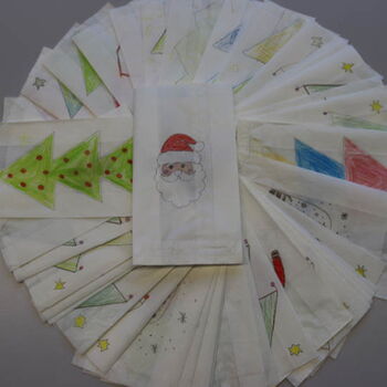 Ein Fächer aus bemalten Weihnachtstüten zeigt Motive wie Weihnachtsbäume und einen Weihnachtsmann.