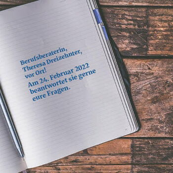 Ein offenes Notizbuch mit einem blauen Stift liegt auf einem Holztisch, der Text informiert über eine Beratung am 24. Februar 2022.