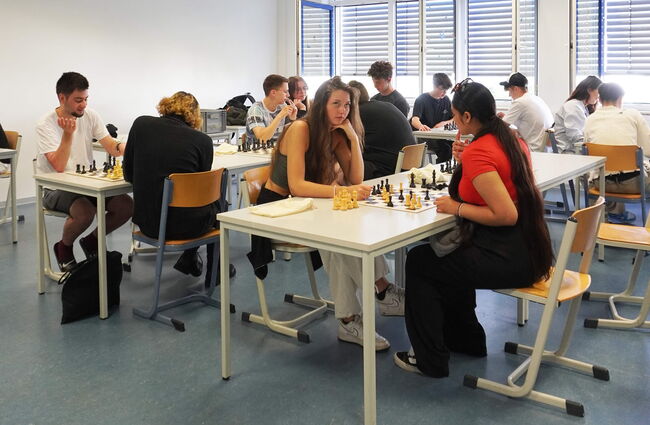 Schüler spielen Schach in einem Klassenraum, während konzentrierte Blicke und strategisches Denken im Vordergrund stehen.