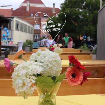 Ein Glasvase mit bunten Blumen steht auf einem Tisch bei einem Tag der offenen Tür am 14.06.2024 im Freien.