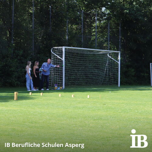 Drei Personen stehen beim Fußballturnier neben einem Tor und unterhalten sich auf dem Rasenplatz der Beruflichen Schulen Asperg.