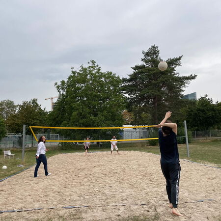 Schüler:innen auf dem Beachvolleyballfeld spielen Volleyball zwei gegen zwei