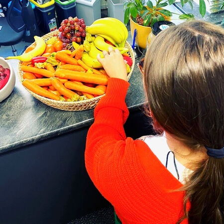 Ein junges Mädchen holt sich Obst aus einem Korb