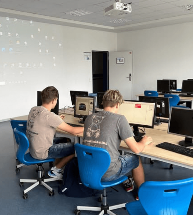 Zwei Schüler arbeiten an Computern in einem modernen Klassenraum während eines Projekttags.