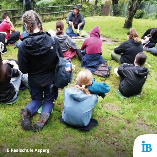 Eine Gruppe von Schülern der Realschule Asperg hört im Schullandheim einem Vortrag im Freien aufmerksam zu.