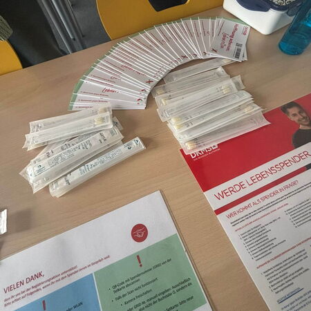 Auf einem Tisch liegen viele Registrierungsunterlagen und Stäbchentests für eine Typisierungsaktion zur Lebensspende aus.