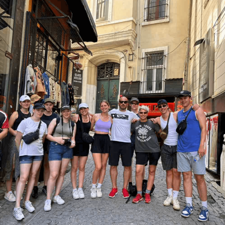 Eine Gruppe von Menschen posiert lächelnd in einer belebten Einkaufsstraße vor historischen Gebäuden.