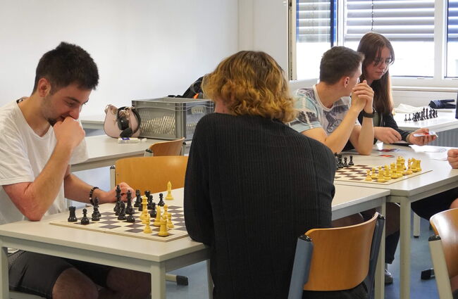 Schüler spielen konzentriert Schach in einem hellen Klassenraum, während sie strategisch ihre Züge planen.