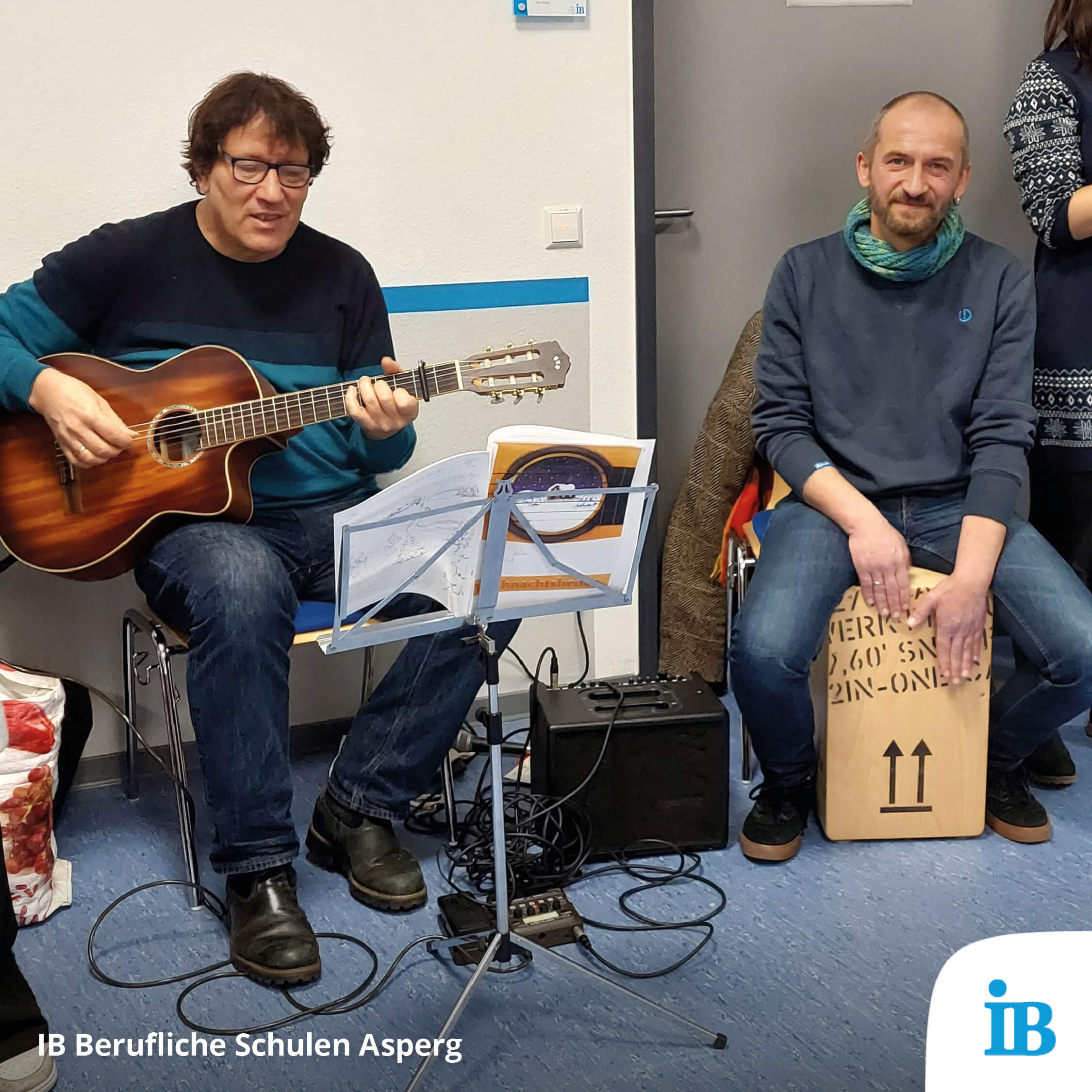 Zwei Männer musizieren bei einer Nikolausaktion, einer spielt Gitarre, der andere sitzt auf einer Cajón.