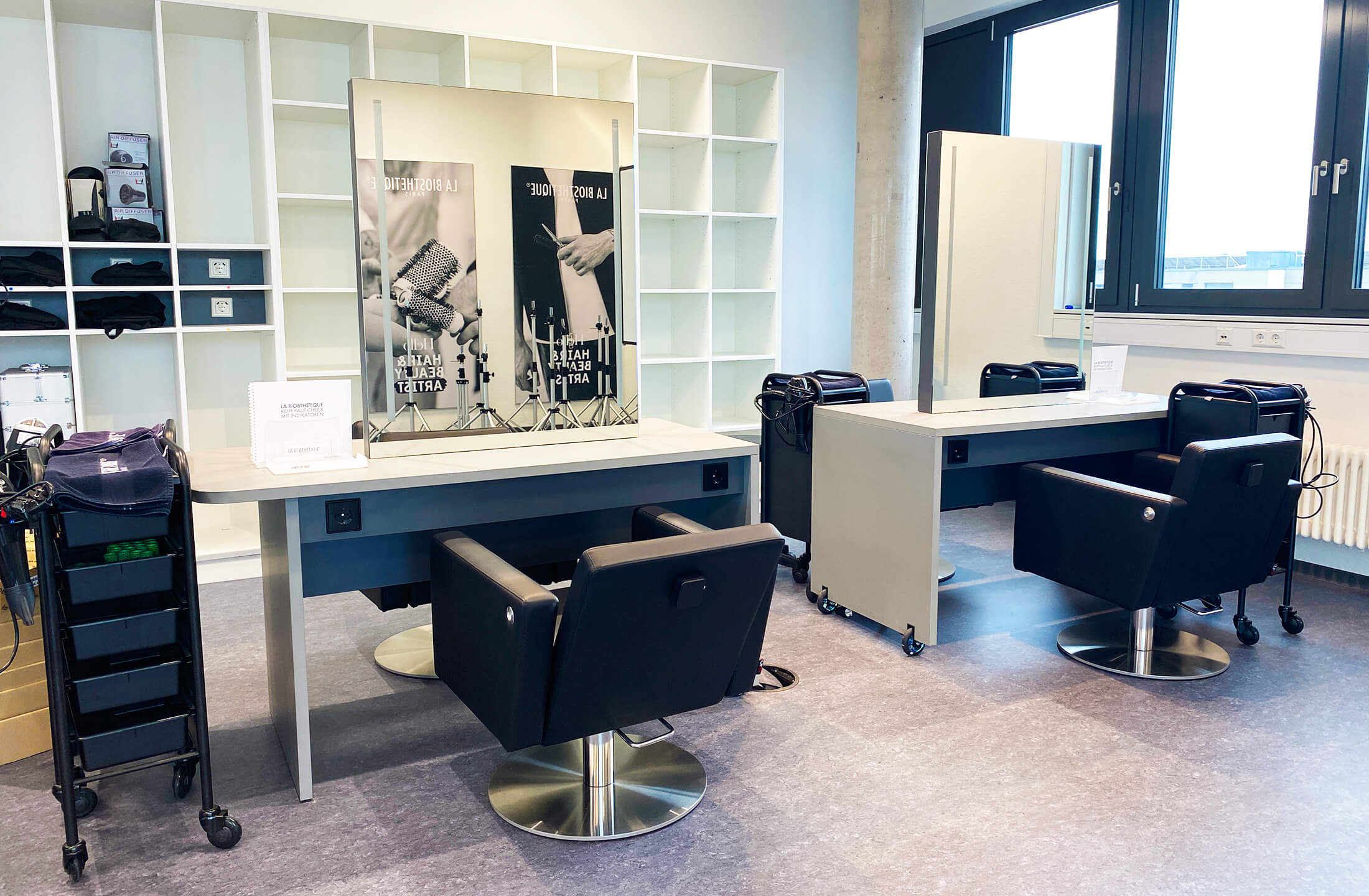 Moderne Friseurstühle und Spiegel in einem hellen Salon von La Biosthetique, bereit für die Kunden.