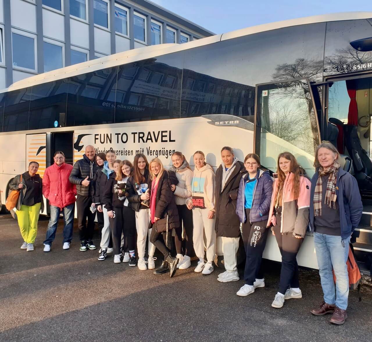 Schüler:innen vor einem Reisebus, kurz vor der Abfahrt